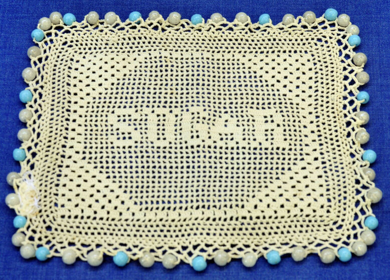 Crocheted bowl covering with blue beads on perimeter
