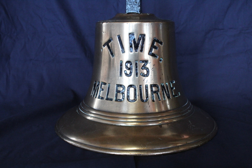 Metal bell with engraved text on blue fabric
