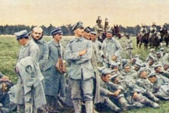 military men form a line and wait seated on the grass