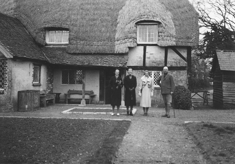 Three team members and Major D.C. Sloan-Stanley standing in the front of the Paulton's Estate, a 14th century English cottage