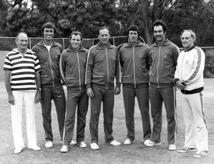 seven squad members standing in row, some in team tracksuit uniforms