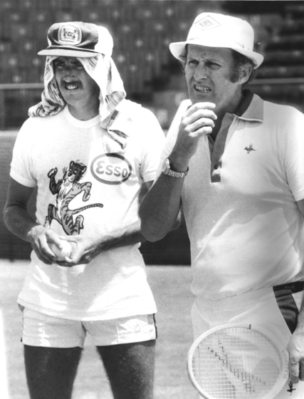 two men standing on the sidelines watching play