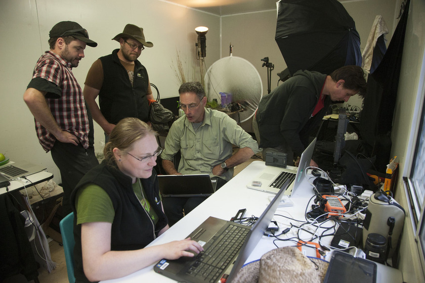 Five scientists in a studio, surrounded by electronic and photographic equipment and laptop computers.