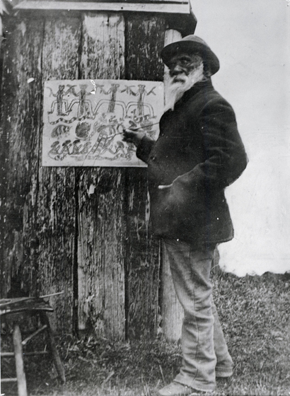 man stands at a hut, as he prepares a painting