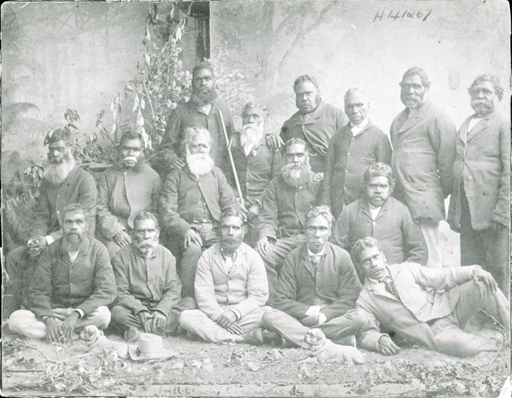 16 formally dressed Aboriginal men pose in formal studio setting