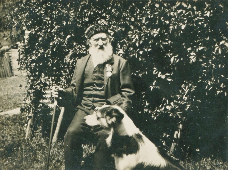 Man with beard seated next to dog