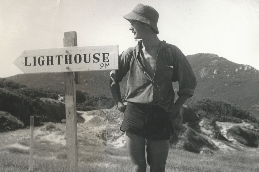 Man standing next to a lighthouse sign