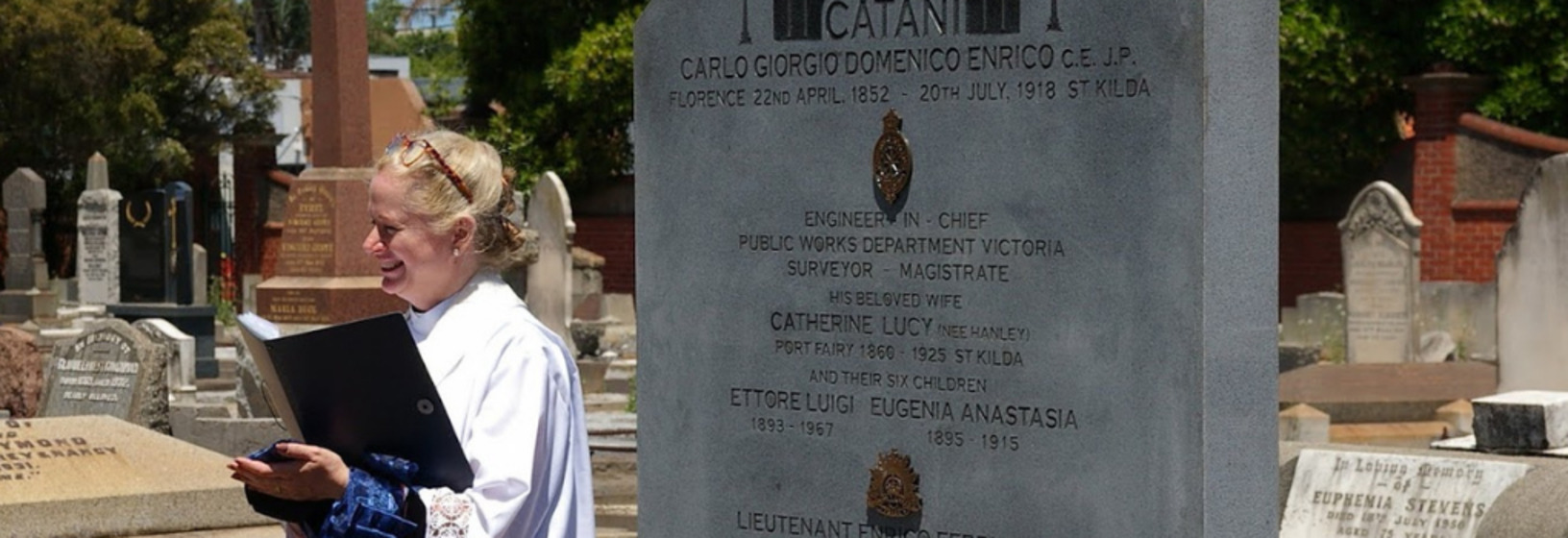 Woman standing in a graveyard presiding over a ceremony