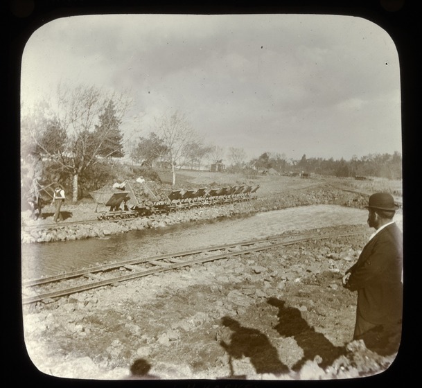Man looking over river works next to rail line