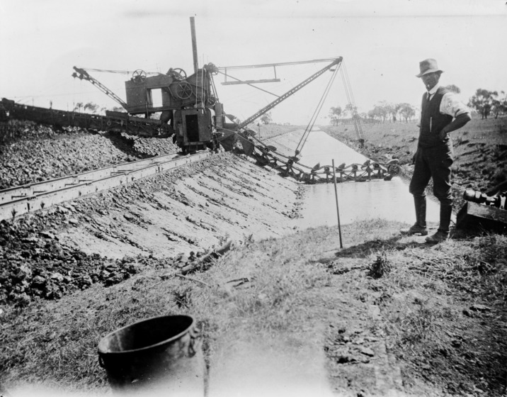a man stands beside a dredge on drain bank