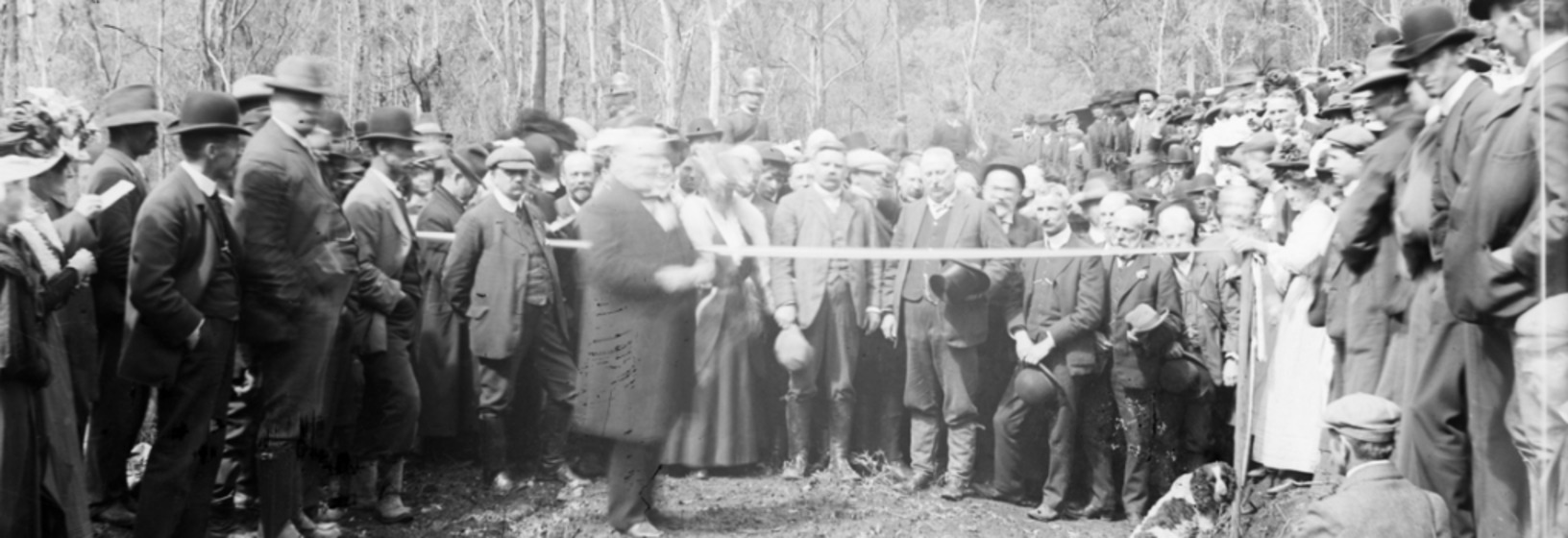 a crowd stands around as a ribbon is formally cut