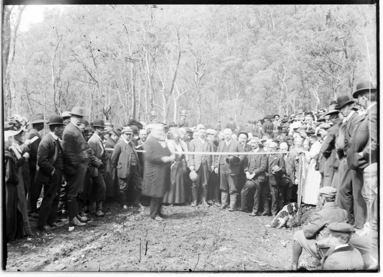 a crowd stands around as a ribbon is formally cut