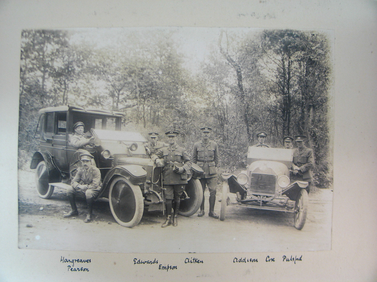 Early model cars parked with people standing to the side