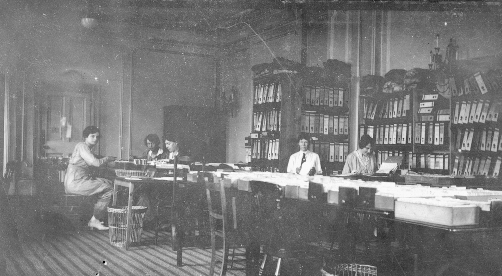 A few women at work at a large table with documents.