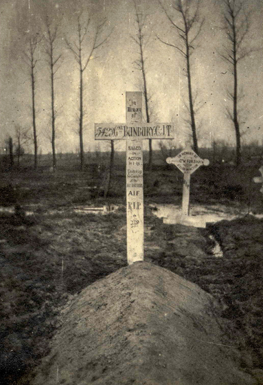 A wooden cross on a new grave in a cemetery in winter