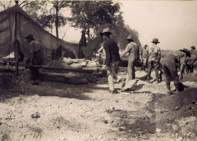 A hessian wrapped body being carried between two men