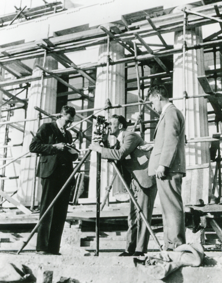 Surveyors with equipment in front of big stone columns
