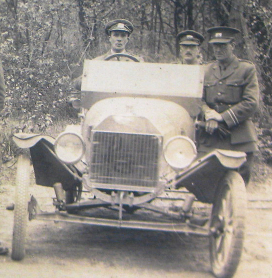 Photograph of a car and a number of men in uniform 
