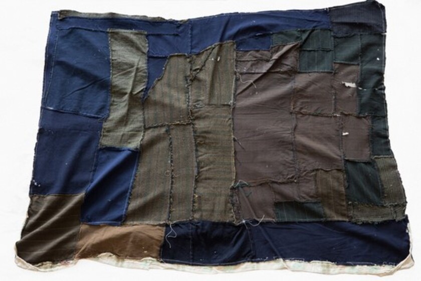 A hand stitched quilt made from recycled coats in blues, brown, black and grey.