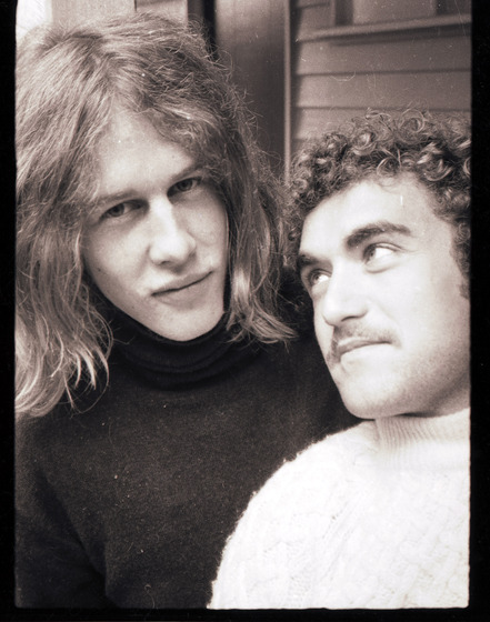 Black and white close up photo portrait of two men, one gazing at the other.