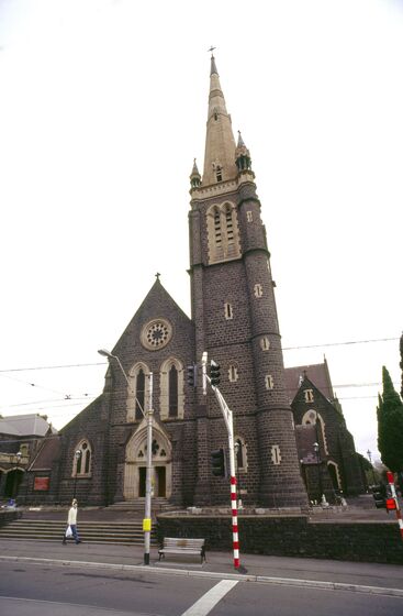 Building facade of brown brick church with steeple/bell tower
