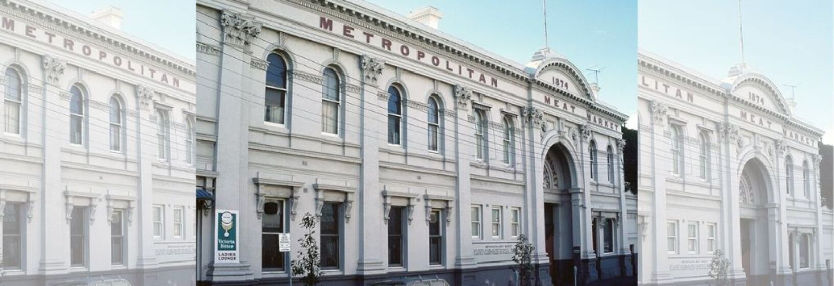 Two story white building with arched entrance way. Writing across the top says Metropolitan Meat Market