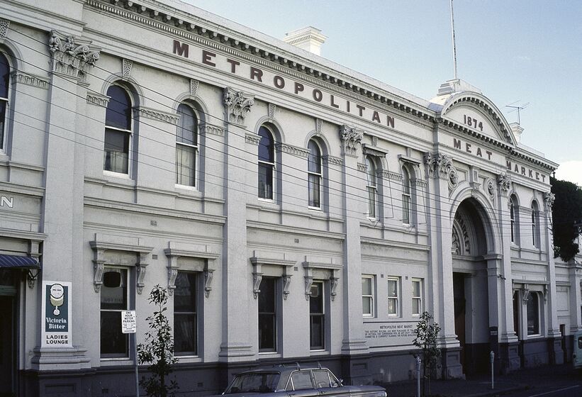 Two story white building with arched entrance way. Writing across the top says Metropolitan Meat Market