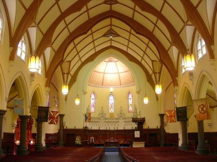 Inside a large open church with an arched roof that features criss cross wooden support beams