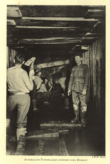 Black and white photograph of a group of soldiers building a wood-lined tunnel, water covering floor.