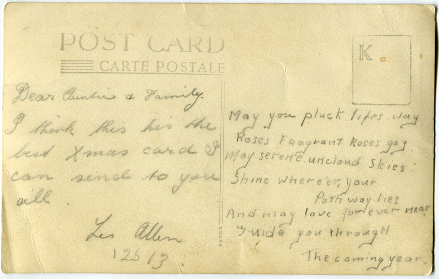 Reverse of a postcard with the handwritten message, 'Dear Auntie and Family. I think this is the best Xmas card I can send to you all. Les Allen. May you pluck life's way Roses, fragrant roses gay. May serene uncloud skies shine where'er your pathway lies. And may love forever near guide you through the coming year.'