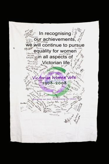 Banner with text 'In recognising our achievements, we will continue to pursue equality for women in all aspect of Victorian life' and the Victorian Women Vote 1908 to 2008 logo with signatures hand written over it.