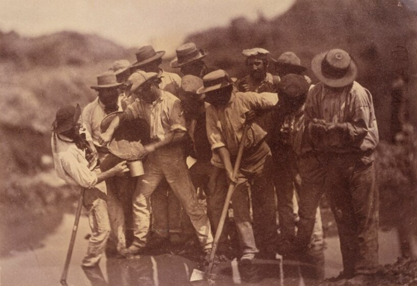 Sepia photograph of a group of miners panning for gold in a creek.
