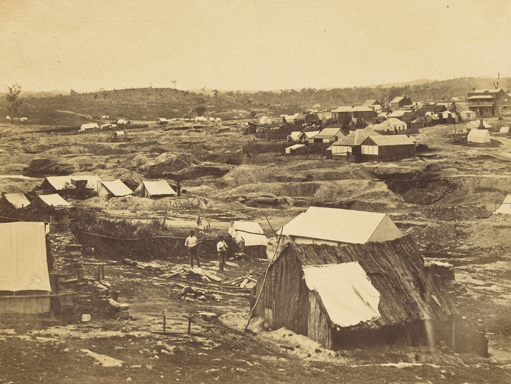 Sepia photograph of goldfields with tents and huts.