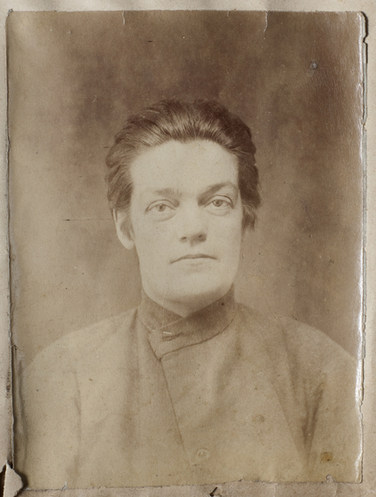 Sepia head and shoulders studio portrait of a woman in a smock with her pulled back.