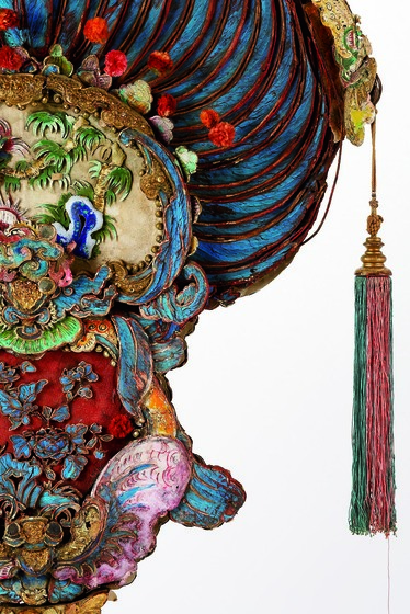 Detail of a colourful processional fan made of feathers and with tassels.
