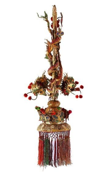 Elaborate gilt and polychrome fleur-de-lis-shaped finial with dragons, butterflies and a fringe.