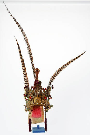 Ornate gilt headdress with mirrors and feathers.