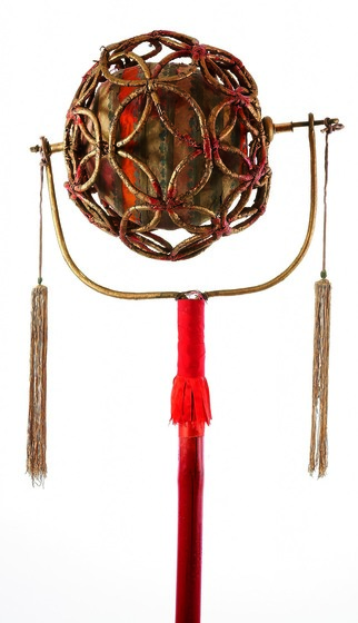 Gilt ball of decorative lattice with a solid ball inside, supported on a pole with tassels.
