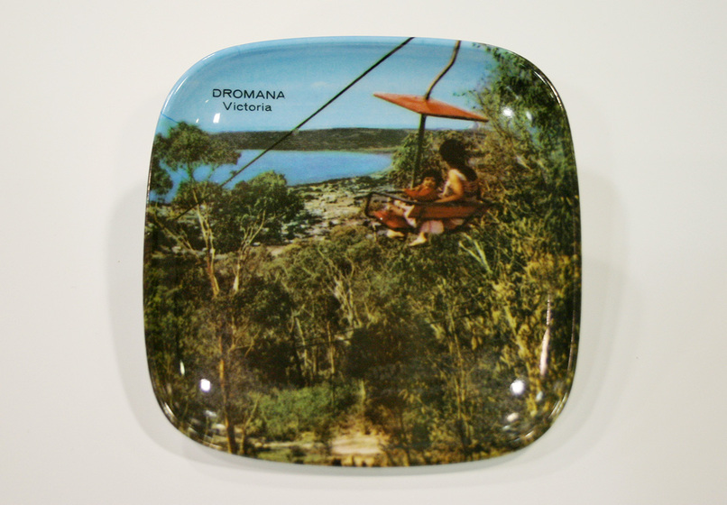 Square plate with inscription 'Dromana Victoria' and colour photographic scene of woman and child in chair lift, surrounded by trees and with a bay in the distance.