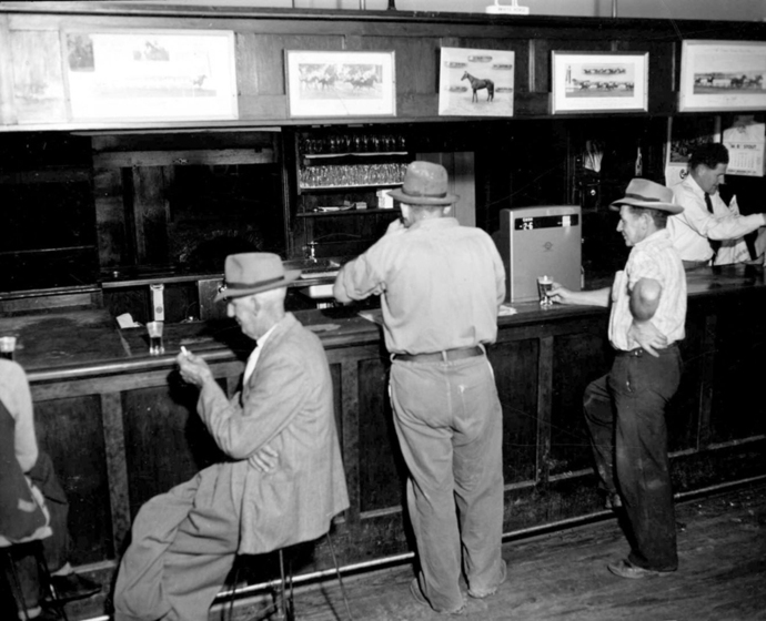 Black and white photograph of three men drinking at a hotel bar.