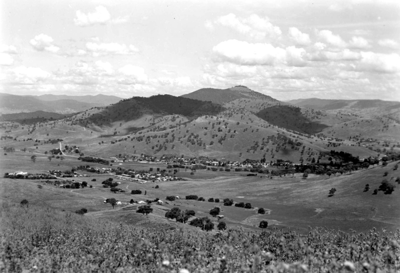 Black and white photograph of a small township in a rural valley from a high vantage point.