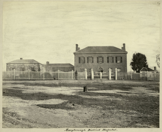 Black and white Victorian photograph of a large two storey Georgian building with shutters on the windows and a picket fence.