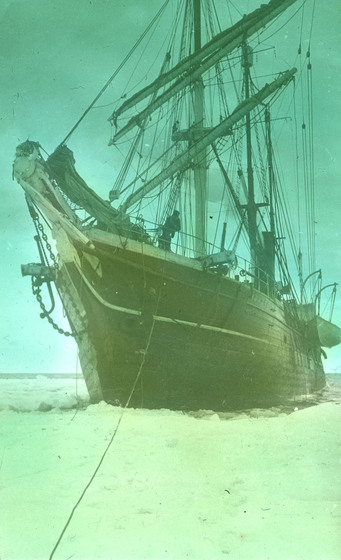 Hand-coloured photograph of a square-rigged sailing ship surrounded by ice.