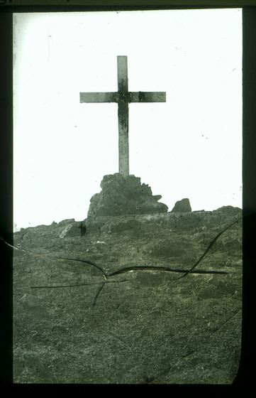 Black and white photograph of a simple cross on a rocky outcrop.