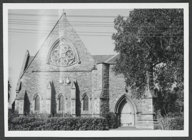 Black and white photograph of the facade of a Victorian Gothic revival stone church.