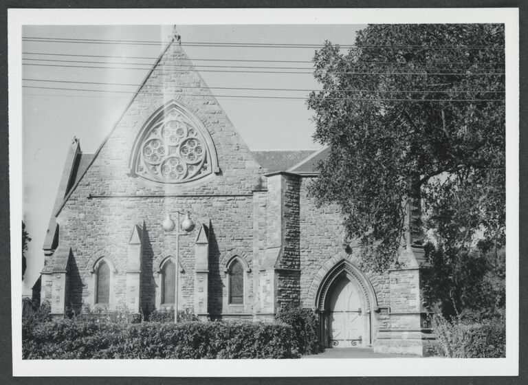 Black and white photograph of the facade of a Victorian Gothic revival stone church.