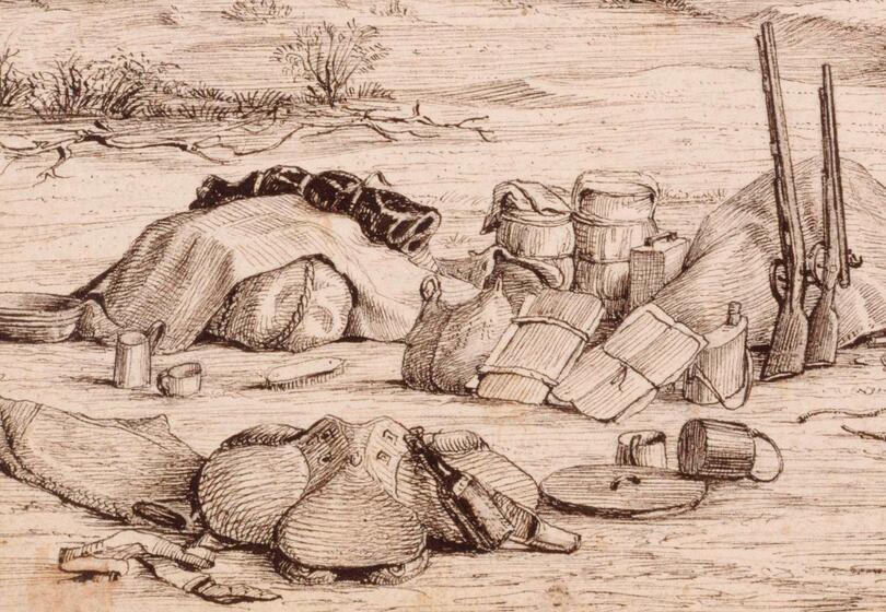 A large pile of equipment, including boxes, water carriers, bags and rifles lie on the ground. There is minimal landscape, indicating the scene is in the desert.