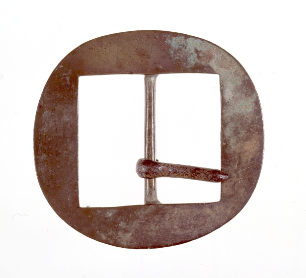 A round metal buckle with two rectangles cut out of the centre. One piece of metal lies horizontal across the rectangle.