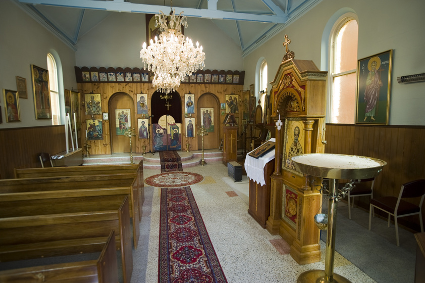Colour photograph of a small Orthodox Christian church with iconostasis and chandeliers.
