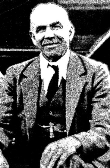 Black and white photograph of a seated elderly man in an Edwardian suit with a fob chain.